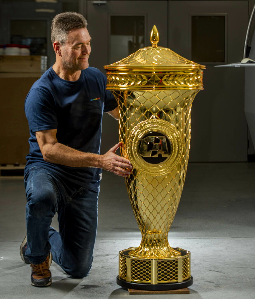 CA Models managing director Clark Campbell kneels next to the Copa Combate trophy